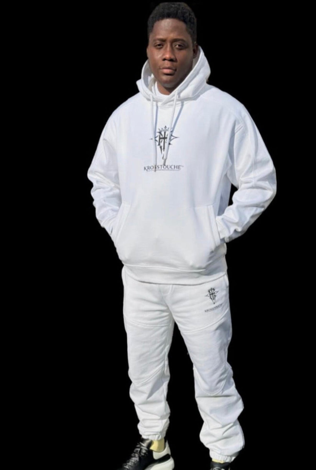 Model wearing KROSSTOUCHE® white hoodie and jogger set on black background