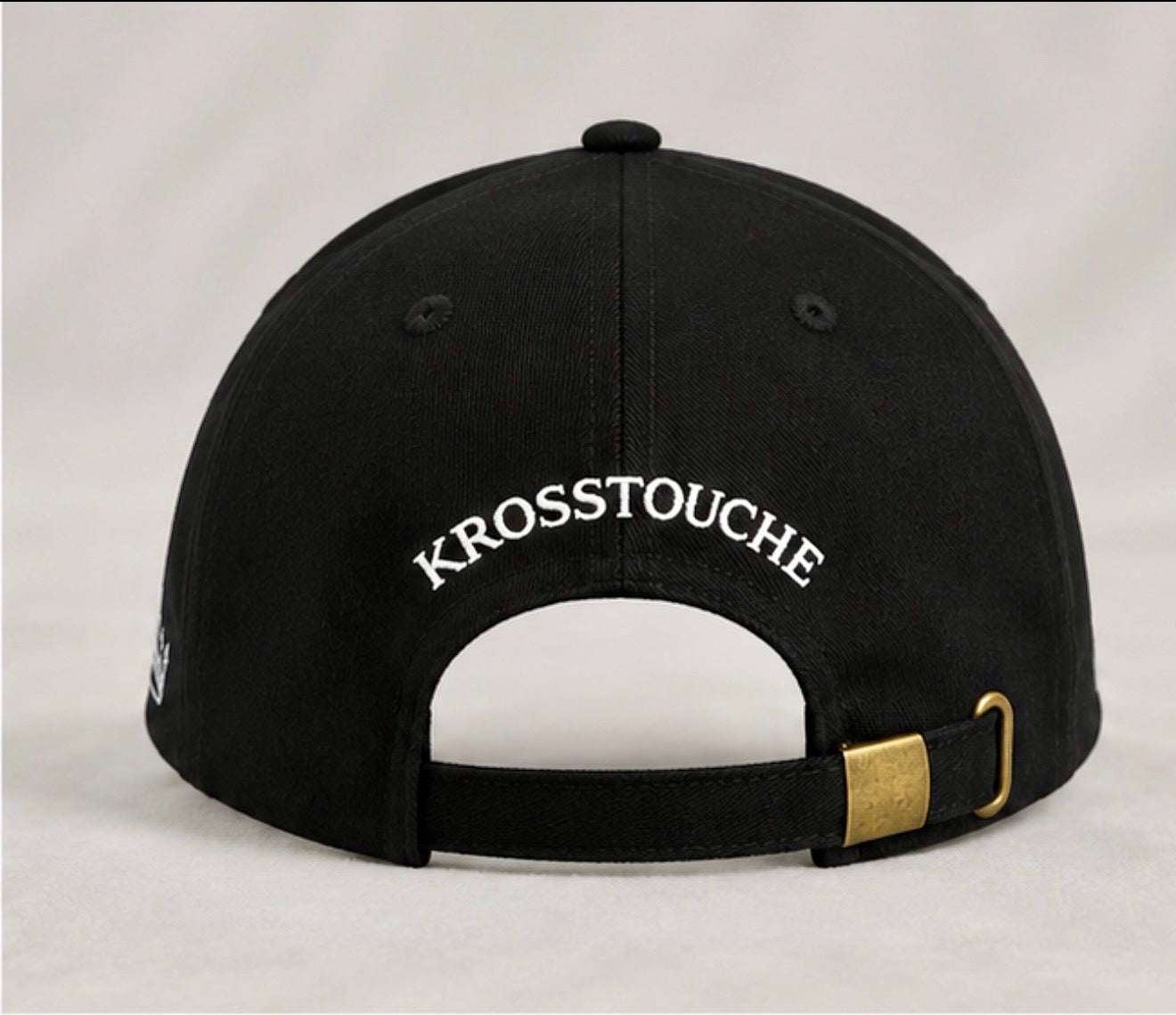 Back view of the KROSSTOUCHE® Signature Black Baseball Cap with embroidered KROSSTOUCHE® branding and adjustable brass buckle.